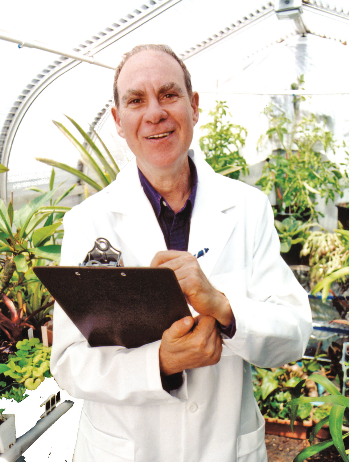 Person in a white lab coat holding a clipboard in a greenhouse setting