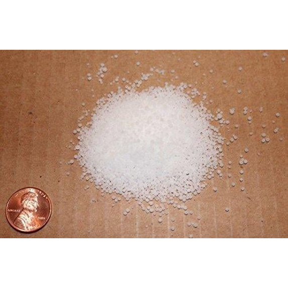 White granular material on a brown surface with a penny for scale