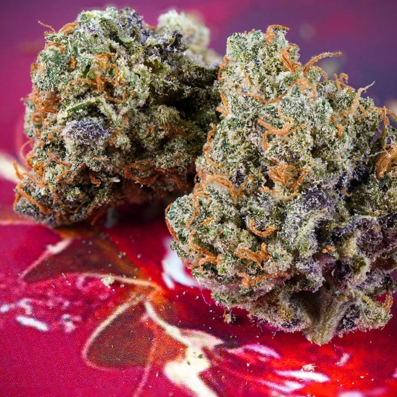 Close-up of cannabis buds on a red surface with a blurred background