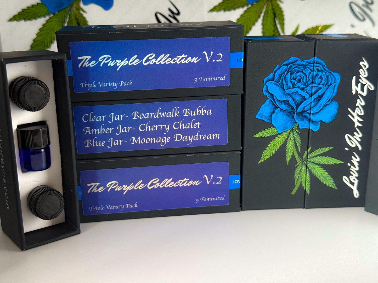Black and blue packaging of 'The Purple Collection V.2' with a blue rose design on a white surface.
