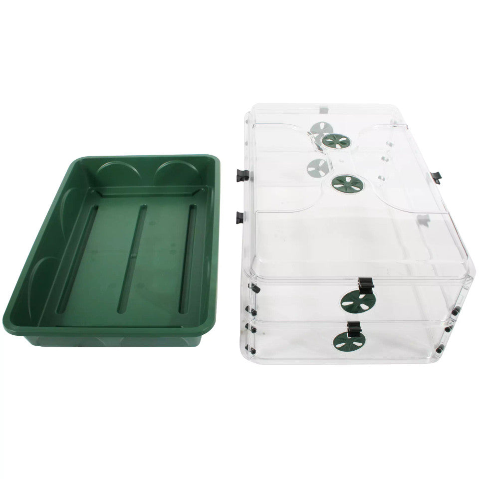 A green plastic tray shown next to a clear acrylic enclosure with green circular ventilation or substrate elements, photographed on a plain white background.